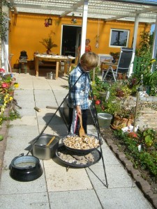 Nach anstrengender wissenschaftlicher Arbeit wendet sich Jonas einer weniger ansruchsvollen Tätigkeit zu und betreut die von Mama vorbereitete Pilzfanne auf dem Dreibock. 