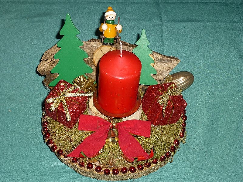 55. - Rundes 1er Gesteck auf Holzscheibe und roter Stumpenkerze, mit Moos, Holzstück, roter Perlenumrandung und Weihnachtsdekoration für 8,00 €.