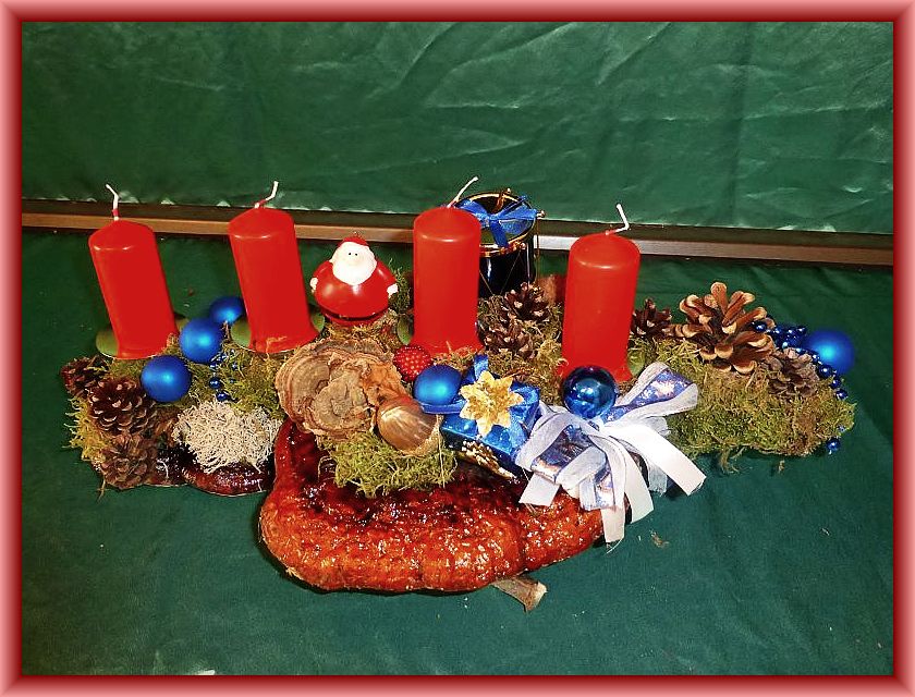 43. Etwa 45 cm langes, bis 25 cm tiefes 4er Gesteck mit roten Stumpenkerzen auf Astgabel mit Rotrandigem Baumschwamm, Schmetterlingstramete, Moos, Rentierflechte, Zapfen und Weihnachtsdekoration zu 12,50 €. 